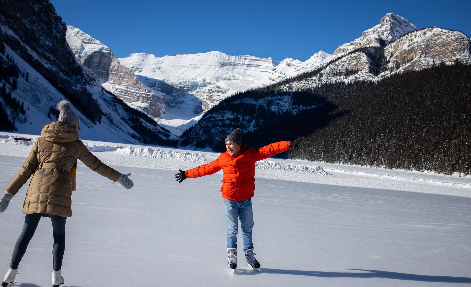 Two people skate on a frozen Lake Louise in Banff National Park in the winter.